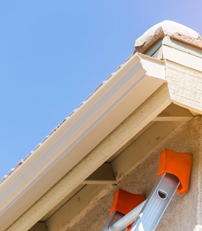 Worker performing Gutter Cleaning Service on a two-story Oviedo - FL home while testing downspout drainage